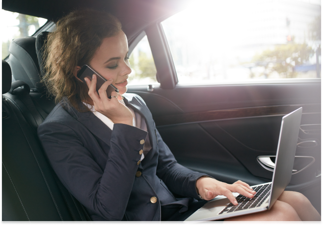 Lady on the phone and computer in an executive car